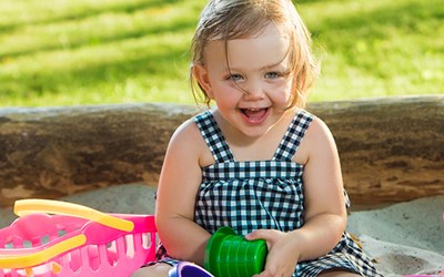Funded childcare for 2 year olds - child sat in sunshine smiling